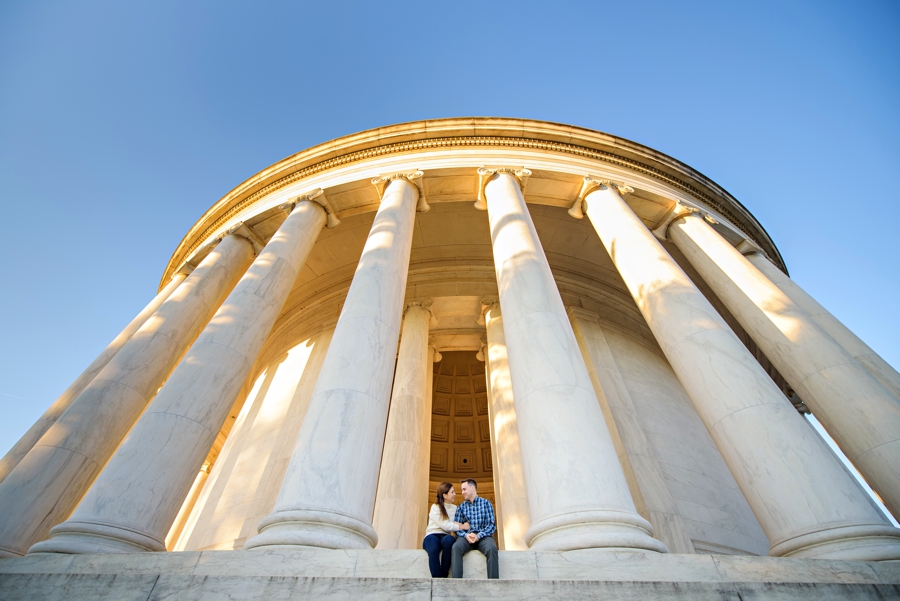An engaged couple sitting on the steps of the lincoln memorial.